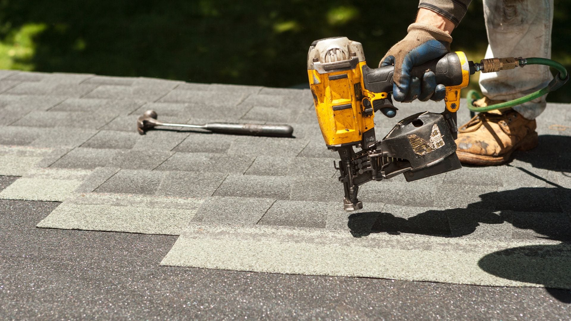 Roofer fastening replacement shingles with a coil nailer during a repair on the Grand Strand