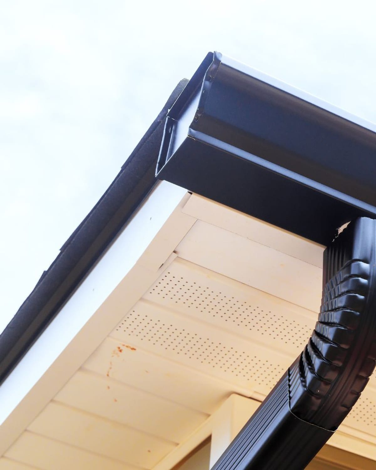 Gutter corner and downspout elbow against a vented soffit on a Carolina home