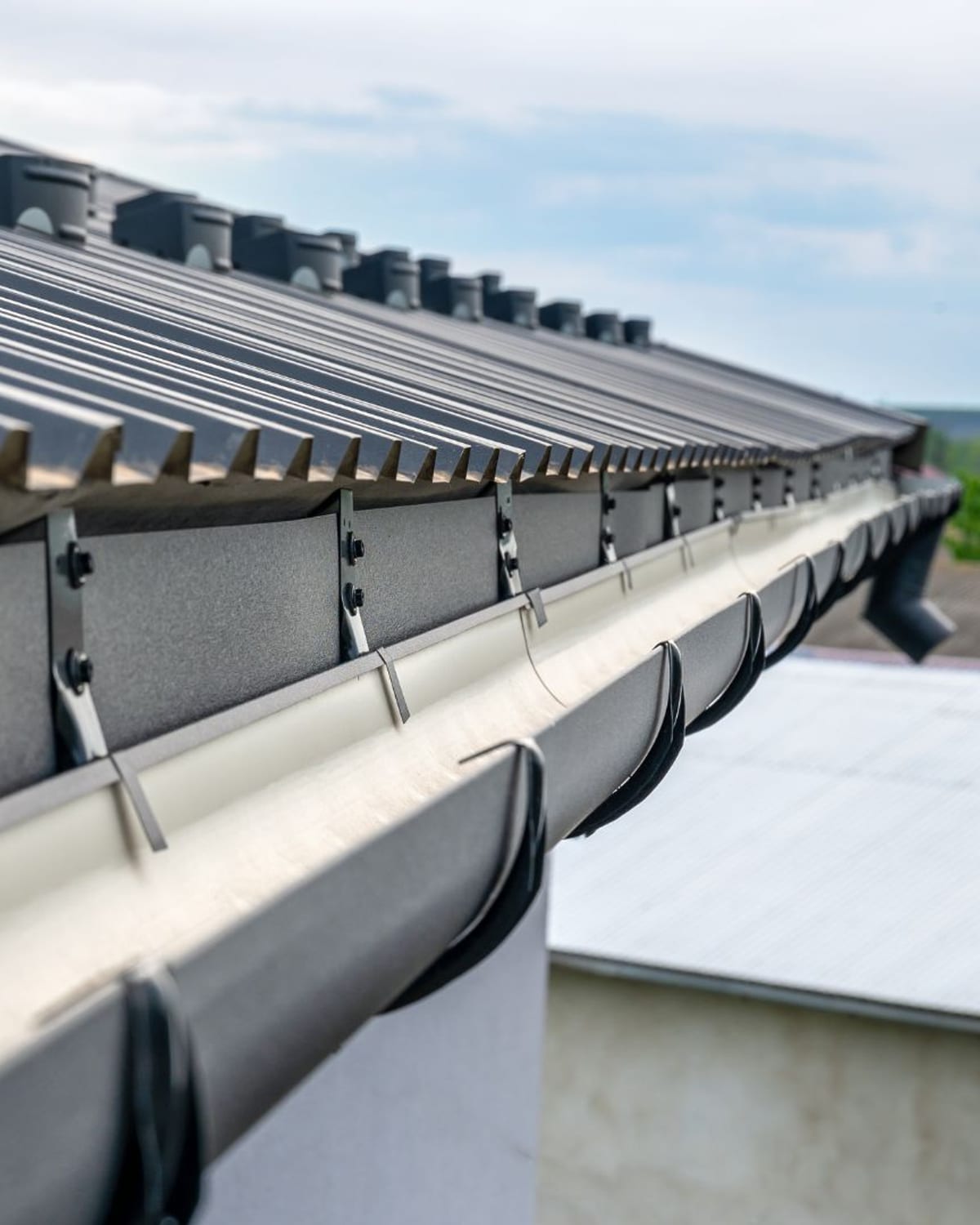 Drip edge and half-round gutter detail along a metal roof edge in coastal Carolina